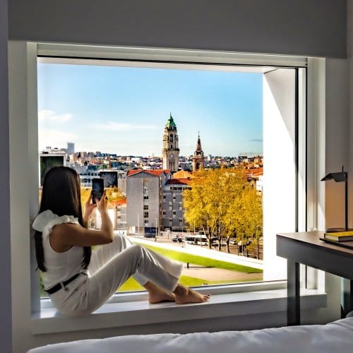 Woman sitting on window sill take a photo of the city