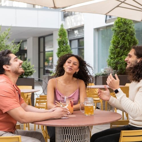 Three friends laugh over drinks