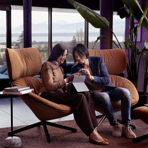 a Couple relax on lounge chairs in an airy hotel lobby