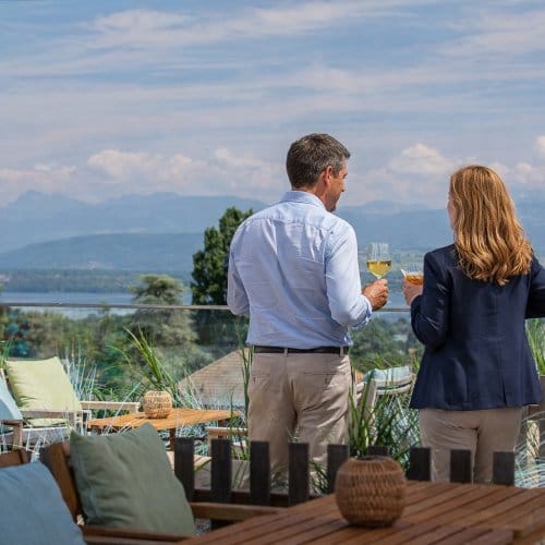 A man and a woman enjoy a rooftop view of the alps