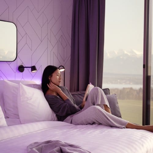 A girl reclined in bed with large windows