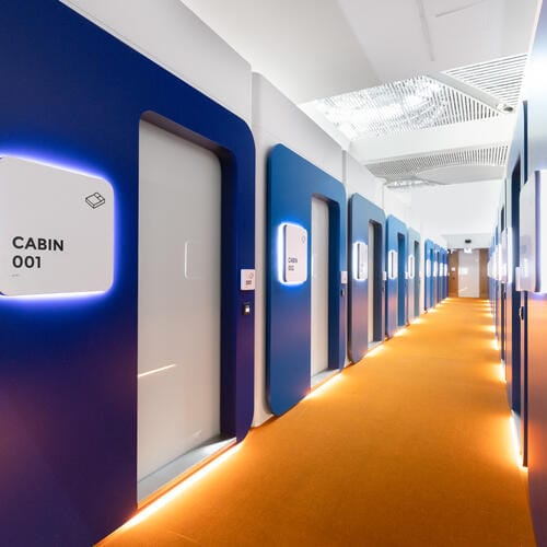 A long modern hotel corridor where each door is signposted by cabin numbers