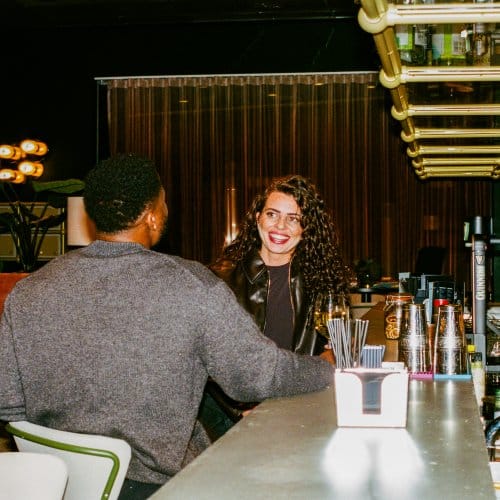 A man and a woman laugh over drinks at a hotel bar
