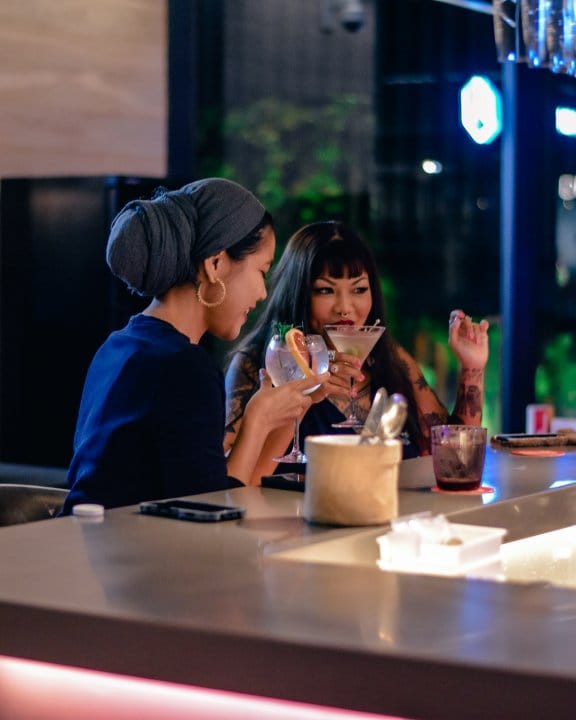 YOTEL Singapore - Two women drinking cocktails at the Komyuniti bar