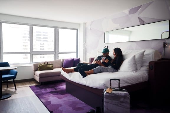 Two people on YOTEL bed looking at their phones
