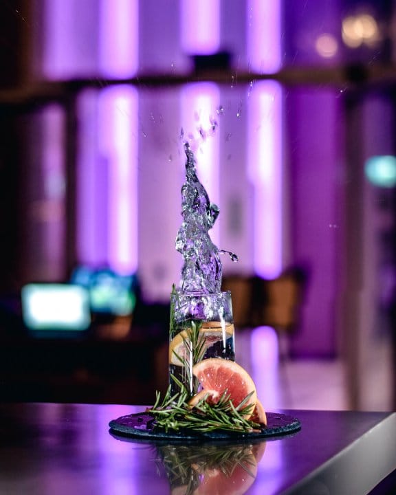 A high ball drink mid-splash with deep purple colours in the background
