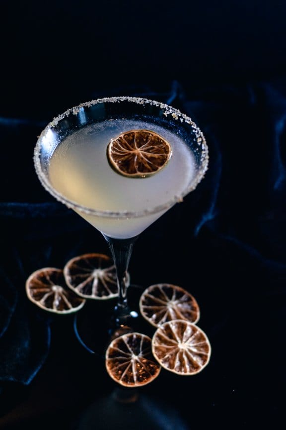 A minimally designed margarita surrounded by fresh fruit for flavour