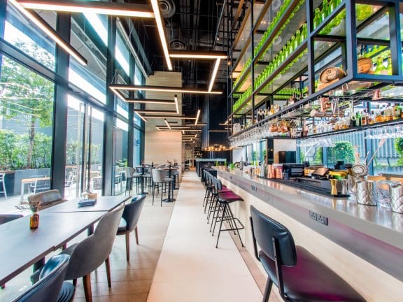 Bright and airy bar with many drinks on display and floor-to-ceiling windows overlooking an outdoor pool