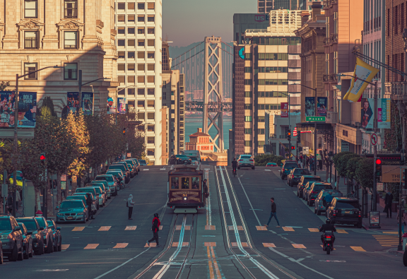 A San Francisco street scene with trams, shops, flags, skyscrapers and hills