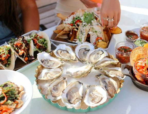 Restaurant table showing oysters, tacos and appetisers