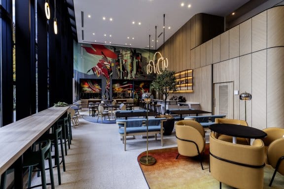 A bright and airy restaurant and bar with greenery, art, and lounge seating