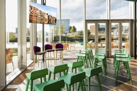A bright meeting room with chairs laid out towards a TV screen