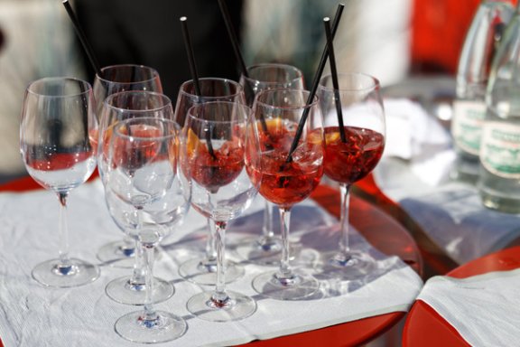 Glasses of Aperol Spritz sit on a tablecloth on a red table
