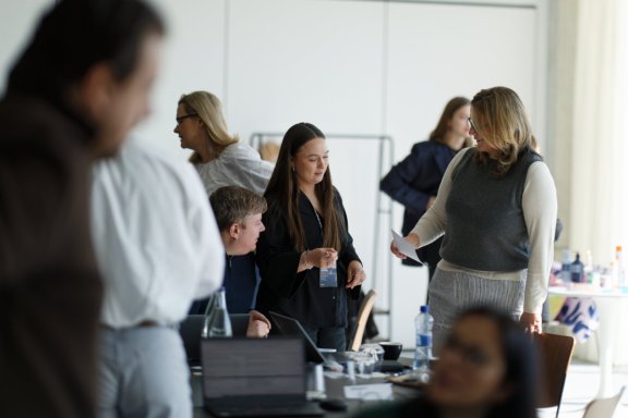 A group o well-dressed people conversing in a smart, clean centre with large windows