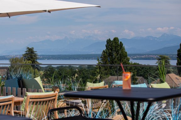 A glass sit on a table with the lake view in the background of a roof terrace