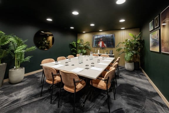A leafy, well decorated meeting room with a large table seating 12