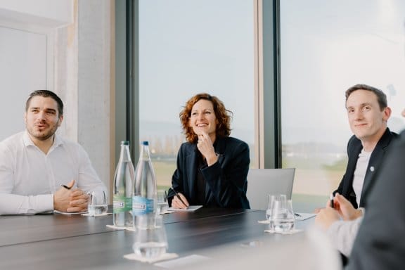 Thress people sitting round a boardroom table