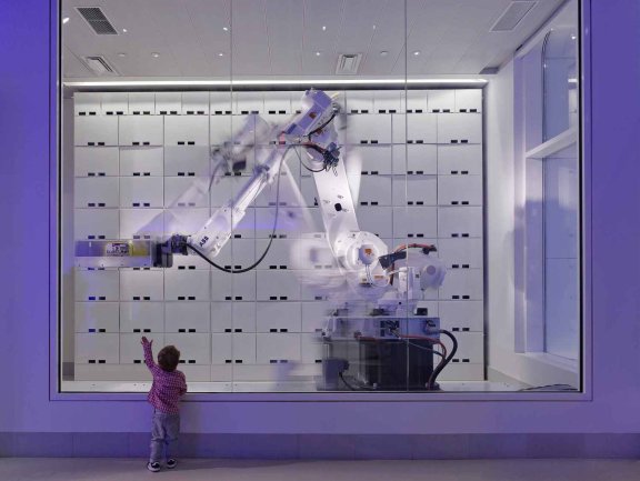 Robots in the NYC Yotel moving a suitcase with a child in the foreground
