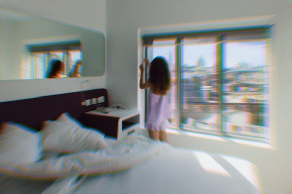 Girl in pyjamas in a hotel room looking out to a view of cetral London