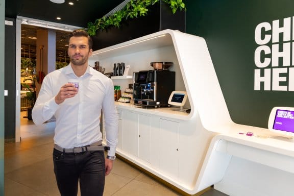 Man standing with coffee cup in front of food and drink display