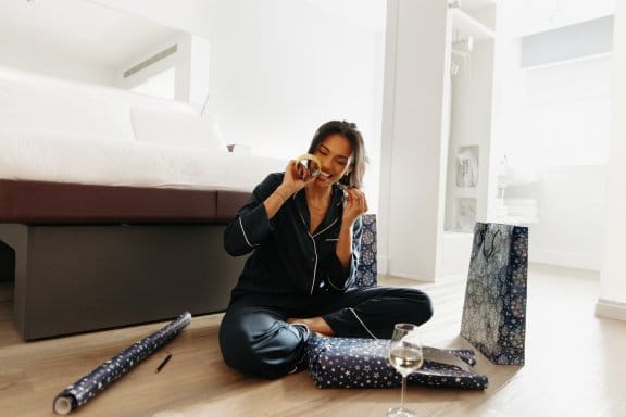 A woman in a hotel room surrounded by Christmas gifts