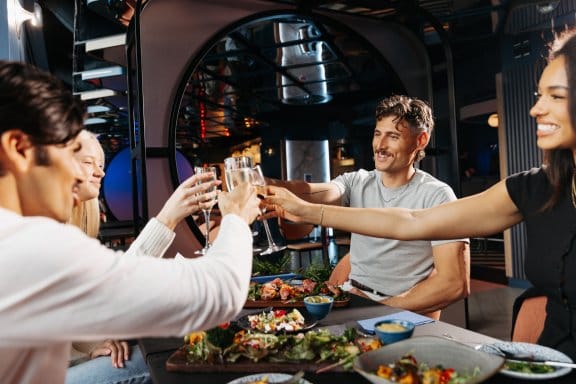 Group of four people toasting surrounded by a food spread