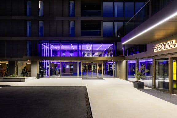 A modern hotel exterior with futuristic purple lights