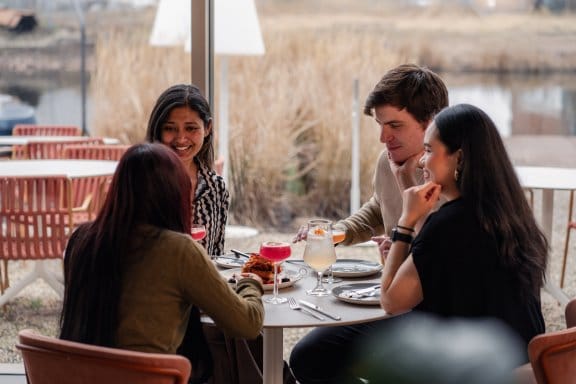Four friends enjoy a meal in a bright and airy restaurant 