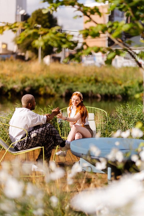 A couple clink their wine glasses by the canal