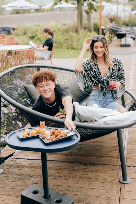 A couple reach for food at an outdoor terrace