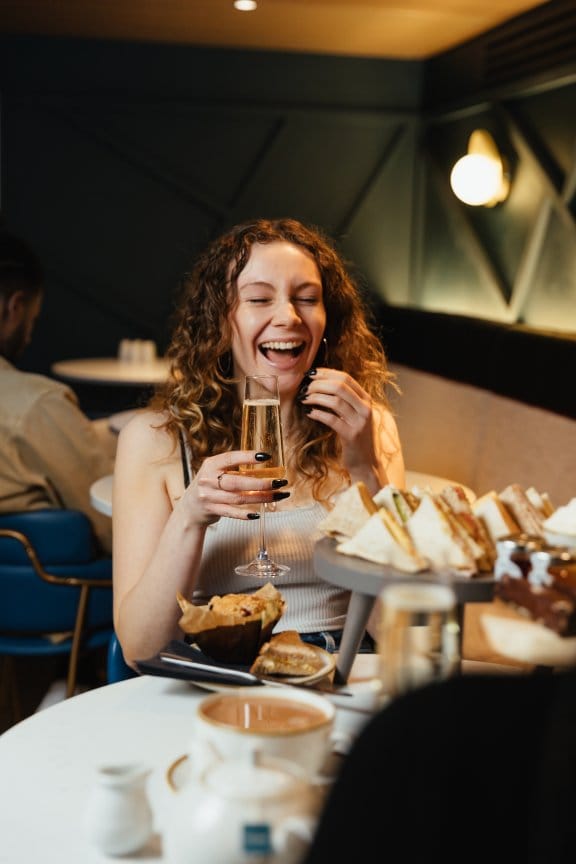 A woman laughs over Champagne