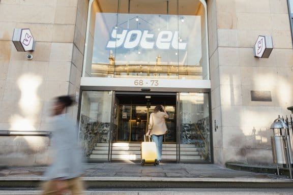 A woman wheels her suitcase into a modern hotel lobby