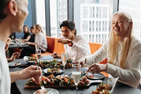 Four friends laugh over the food in a high-rise restaurant