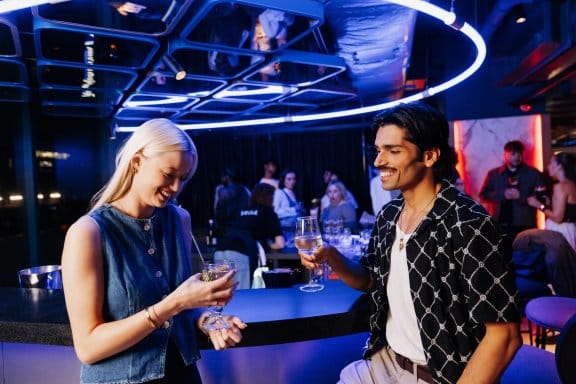 A girl and a man chat at a vibrant circular bar
