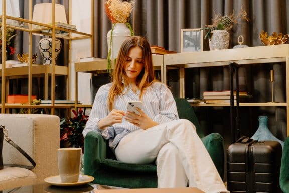 A woman relaxes in a hotel lounge as she plays on her phone 