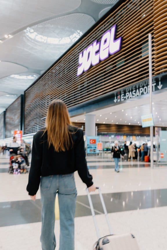 A woman walks towards the front of a large airport hotel. The lettering reads YOTEL