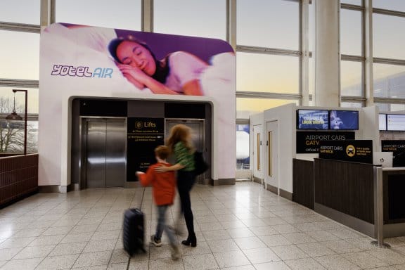 A woman and her child walk into the front entrance of an airport hotel