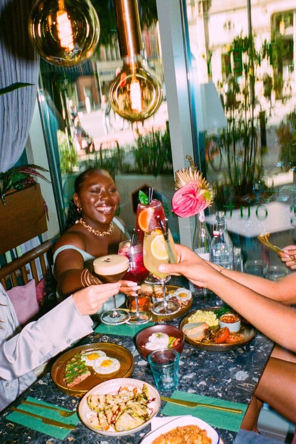 Four friends clink their glasses in an eclectic restaurant