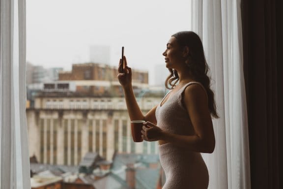 A woman takes a photo of central Manchester from a large hotel window