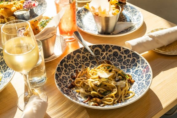 Cream of mushroom linguine, white wine and cocktails on a table