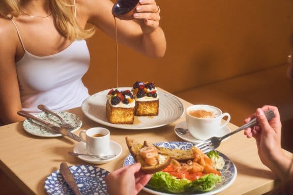 A girl pour syrup on her cake during a buffet breakfast meal