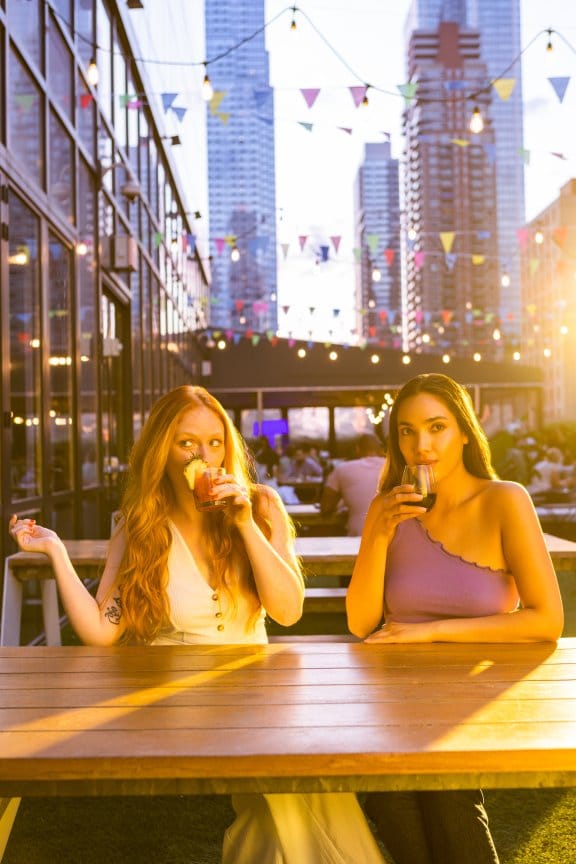 Two friends enjoy a rooftop drink in New York