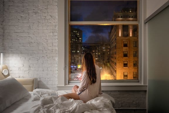 A girl relaxes in her hotel bed and admires the view of San Francisco