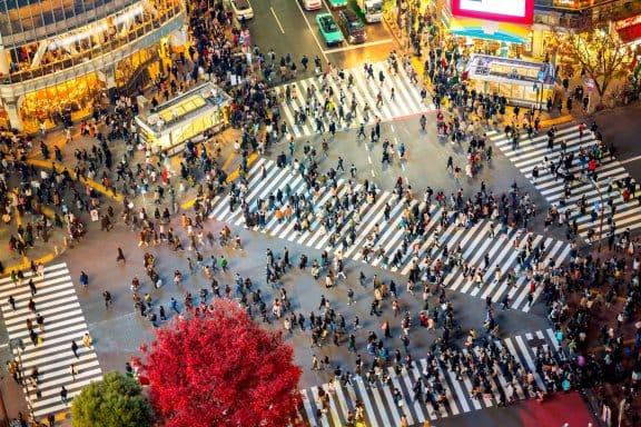 A crowd of people cross a vibrant street in Tokyo