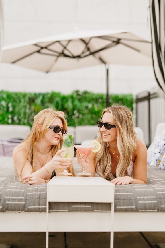 Two girls relax on a sun lounger and chat over cocktails