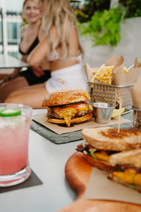 Two woman talk by the pool with burgers and canapes in the foreground