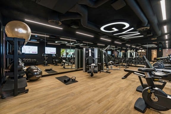 Hotel gym with dark walls, wooden floors and various exercise machines