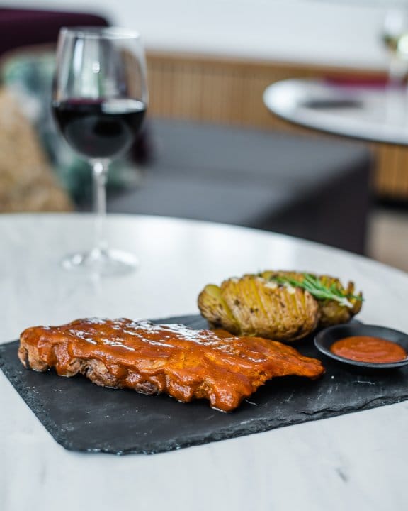 Plate of ribs and roasted potatoes with a glass of red wine