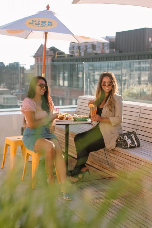 Two girls share a drink on a rooftop bar