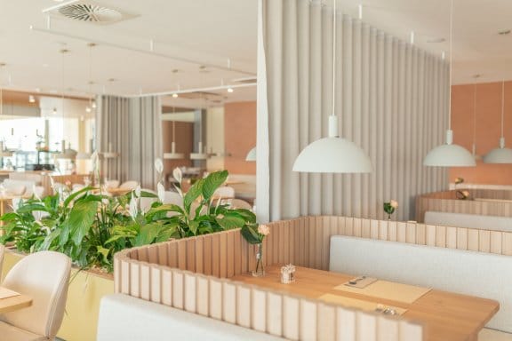 A leafy restaurant area with bamboo seating and white decor